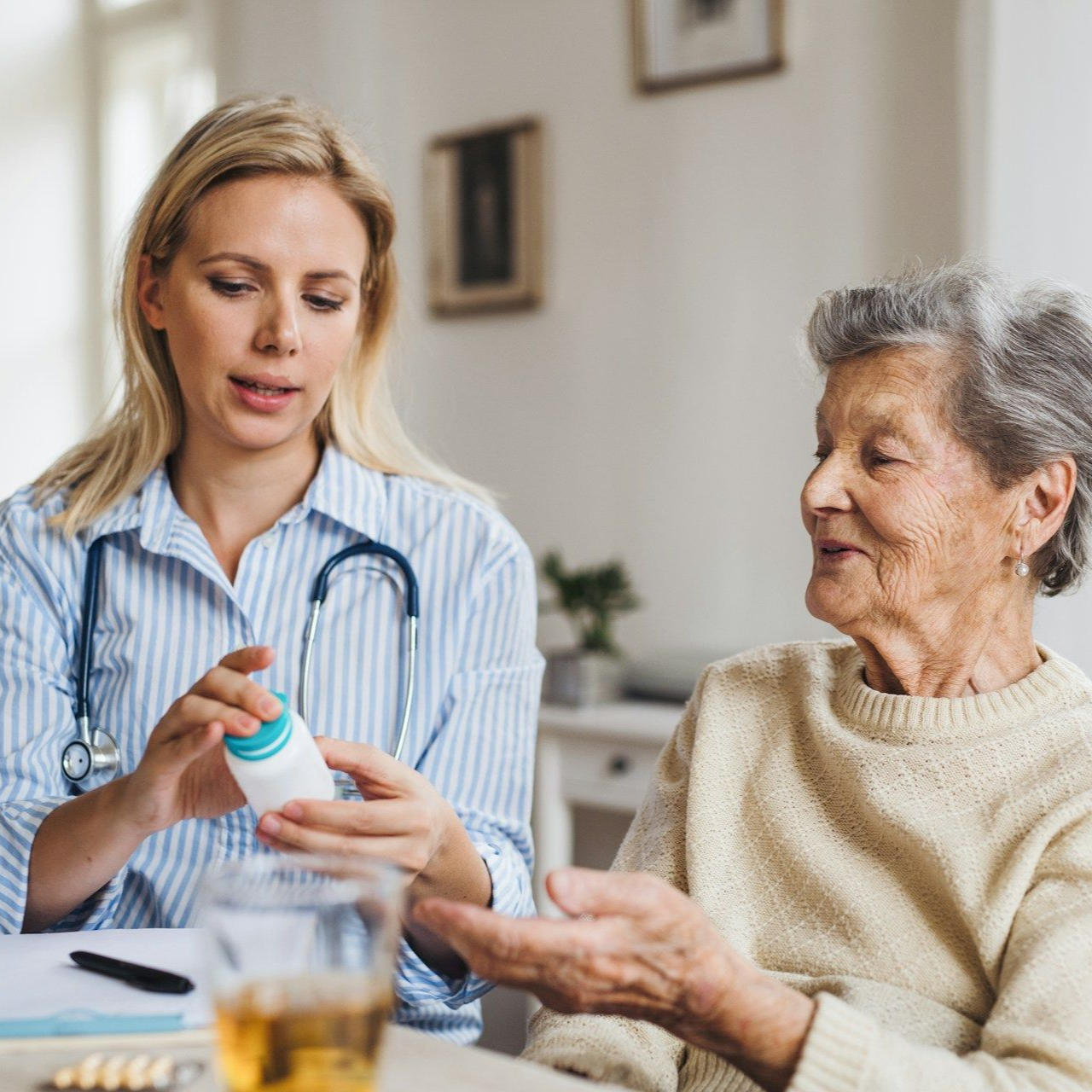 A healthcare provider shows medicine to a patient indoors. The patient appears elderly.