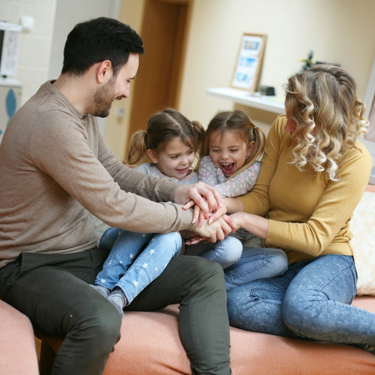 Family, smiling, sitting on a sofa, playing a hand-stacking game.