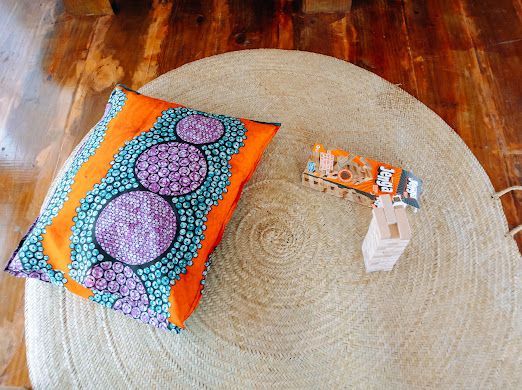 A pillow is sitting on a round rug on a wooden floor.