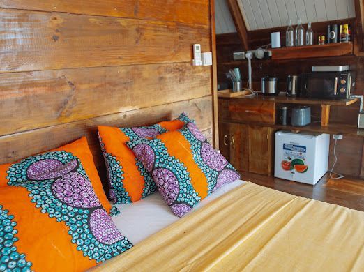 A bed with purple and orange pillows in a wooden room