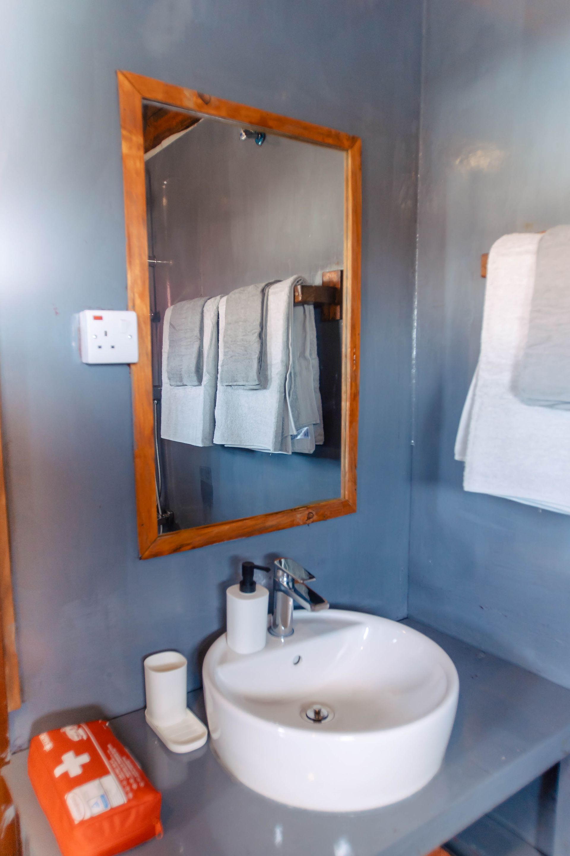 A bathroom with a sink , mirror and first aid kit.
