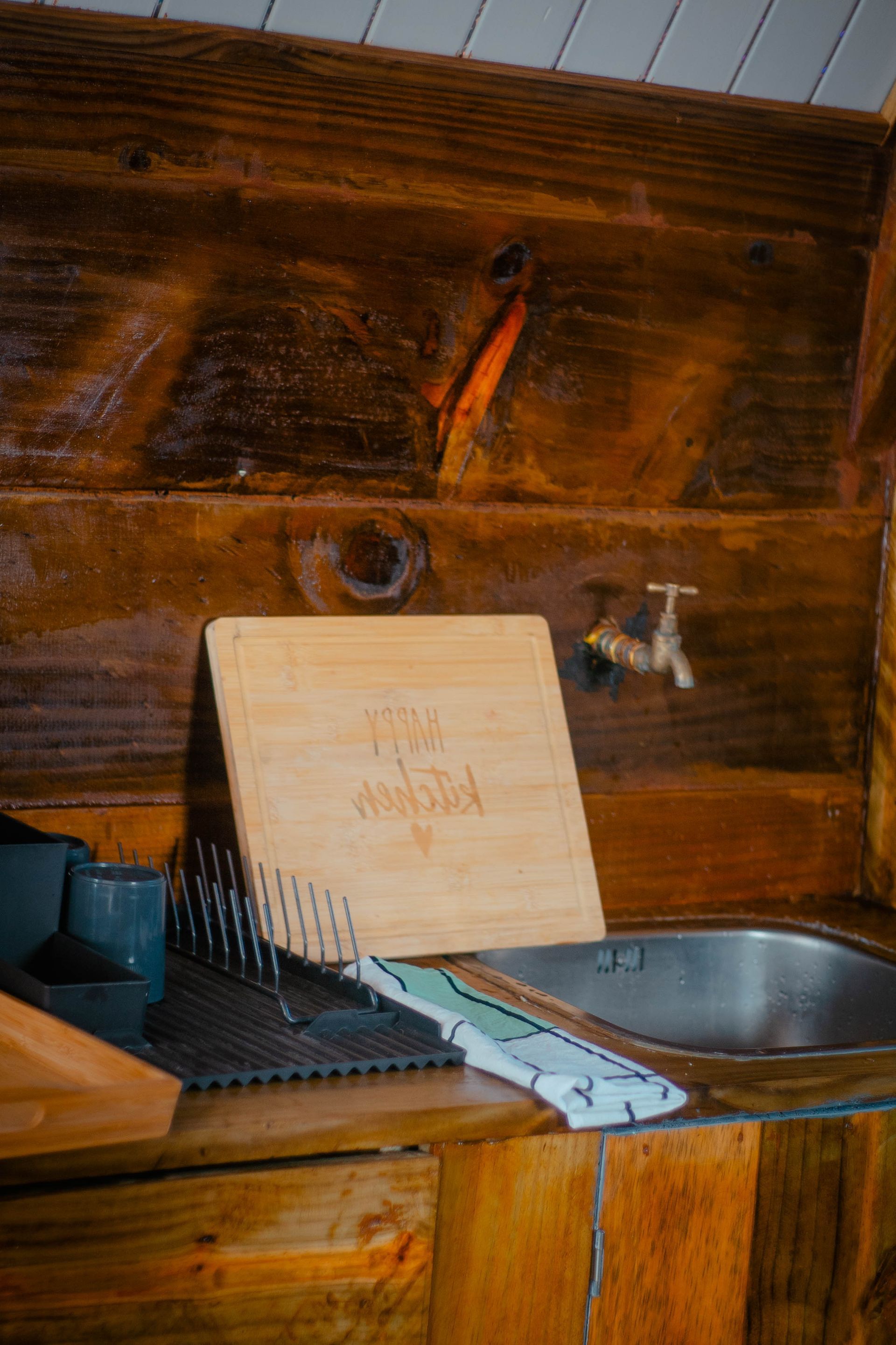 A cutting board is sitting on top of a wooden counter next to a sink.