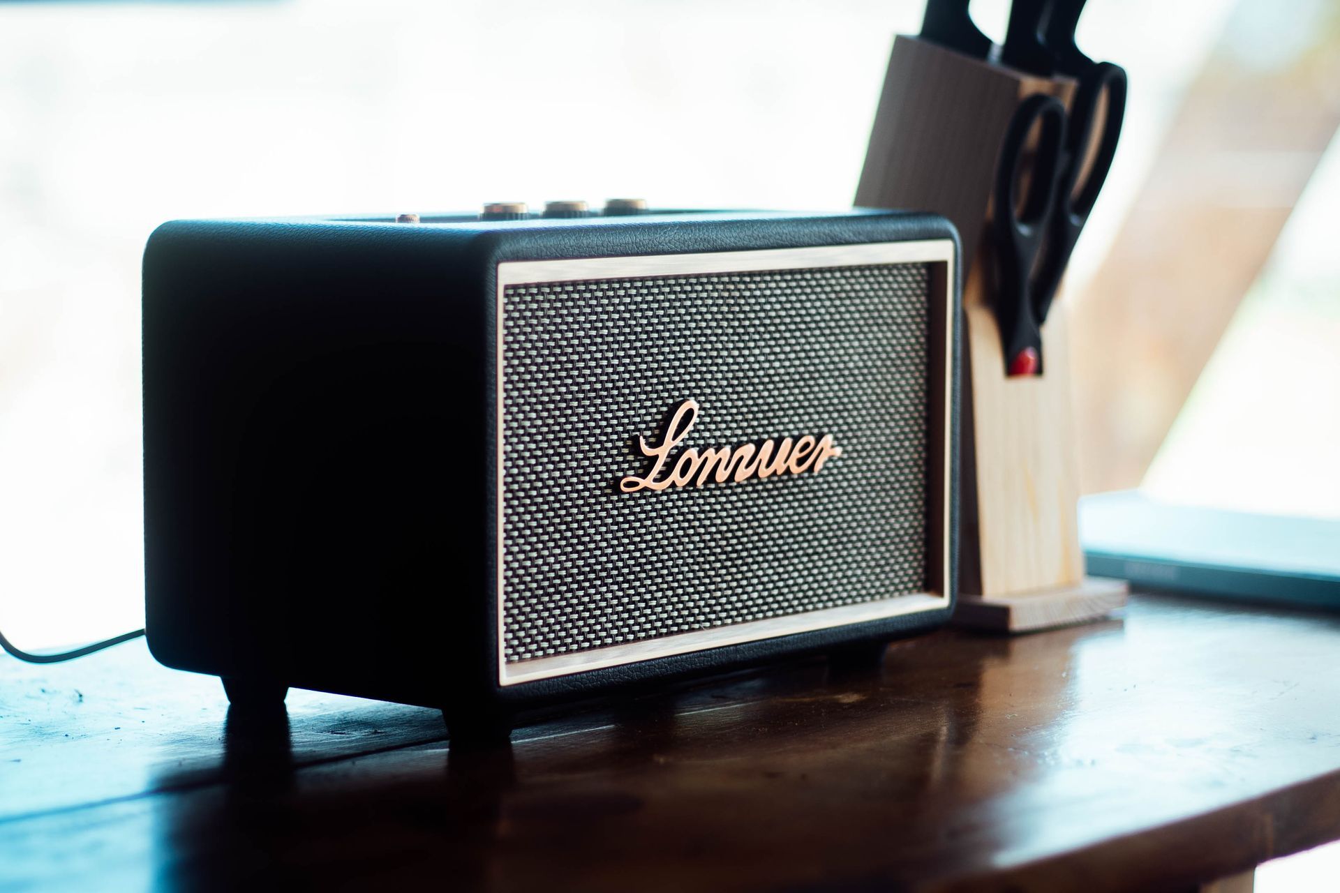 A black marshall speaker is sitting on a wooden table.