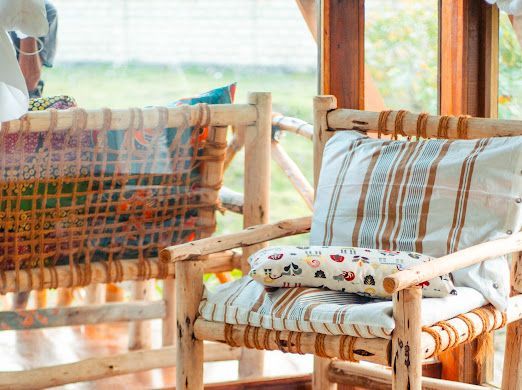 Two wooden chairs with pillows on them are sitting next to each other in front of a window.