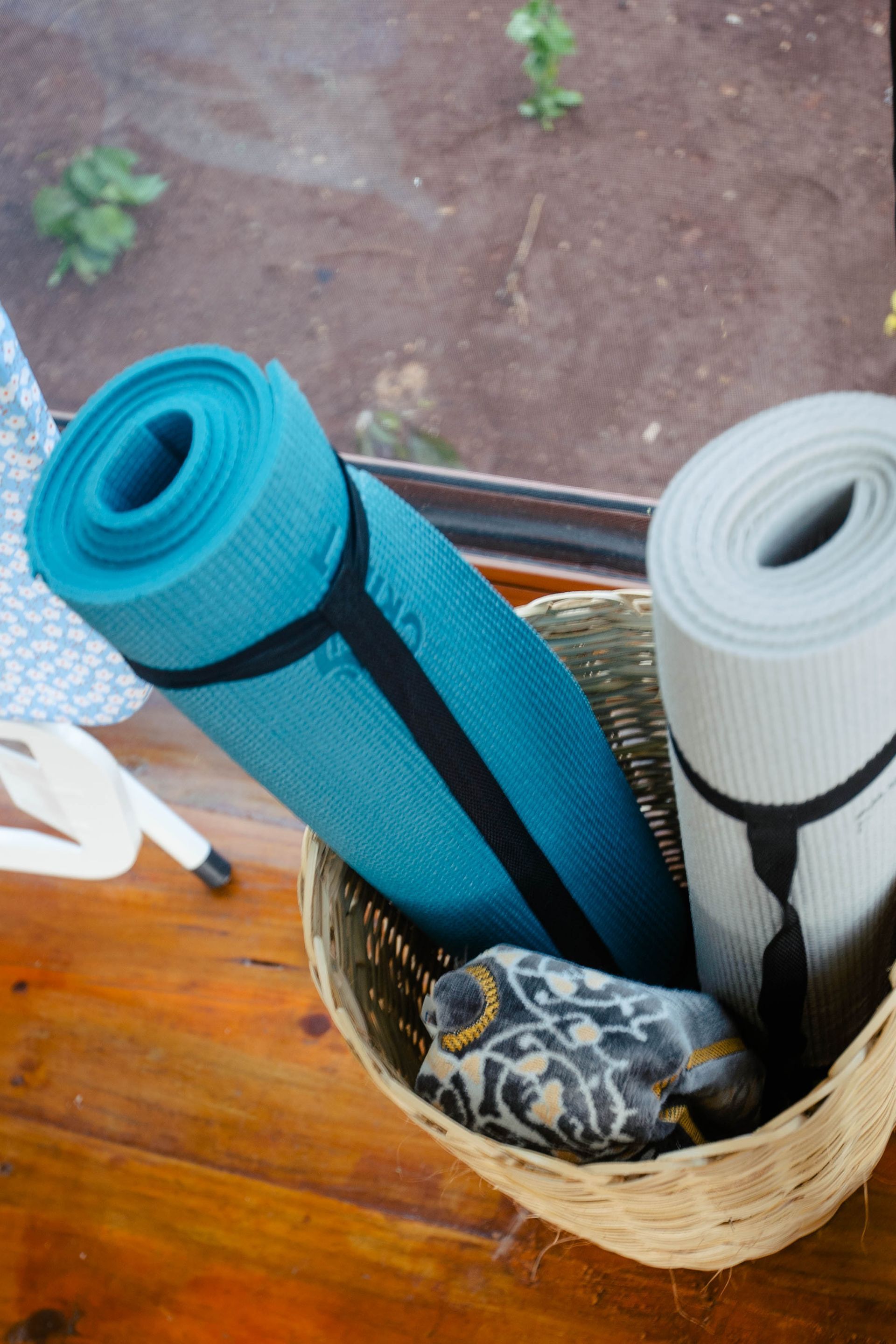 Two yoga mats are in a basket on a wooden table.