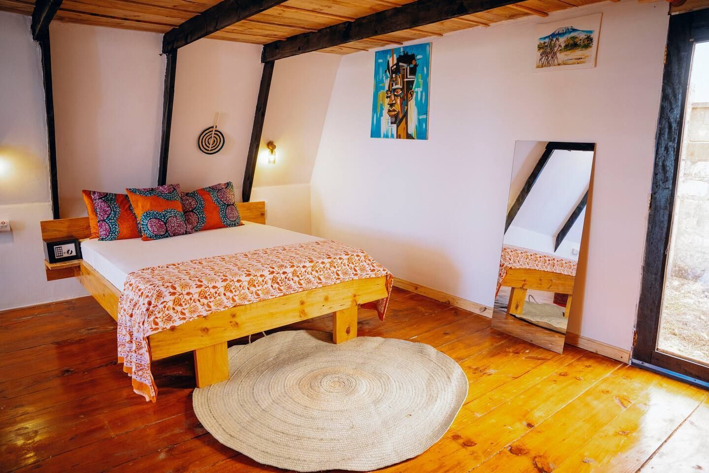 A bed with purple and orange pillows in a wooden room