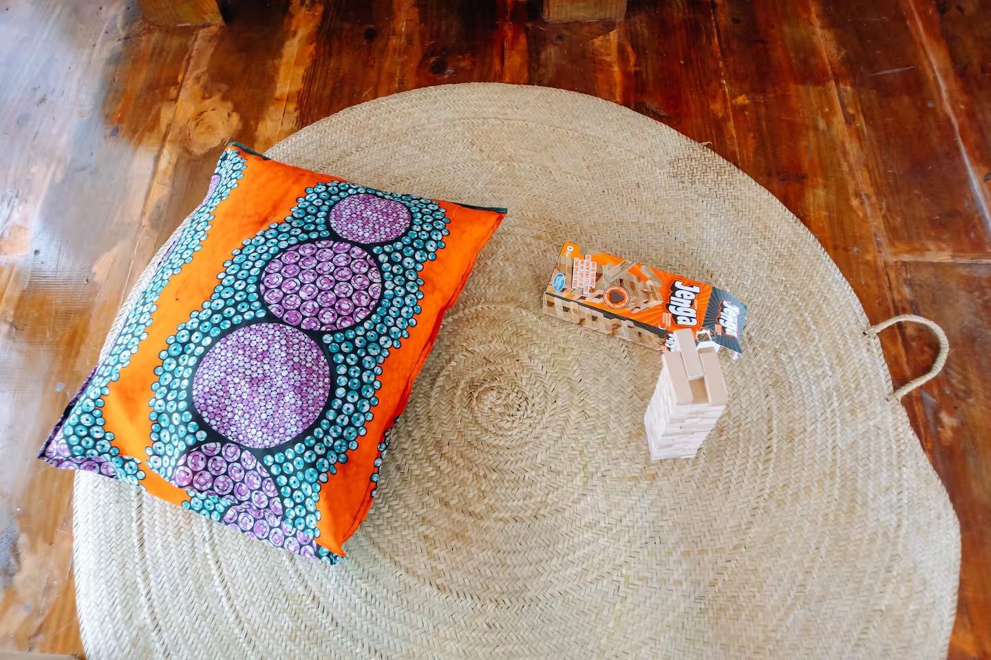 A pillow is sitting on a round rug on a wooden floor.