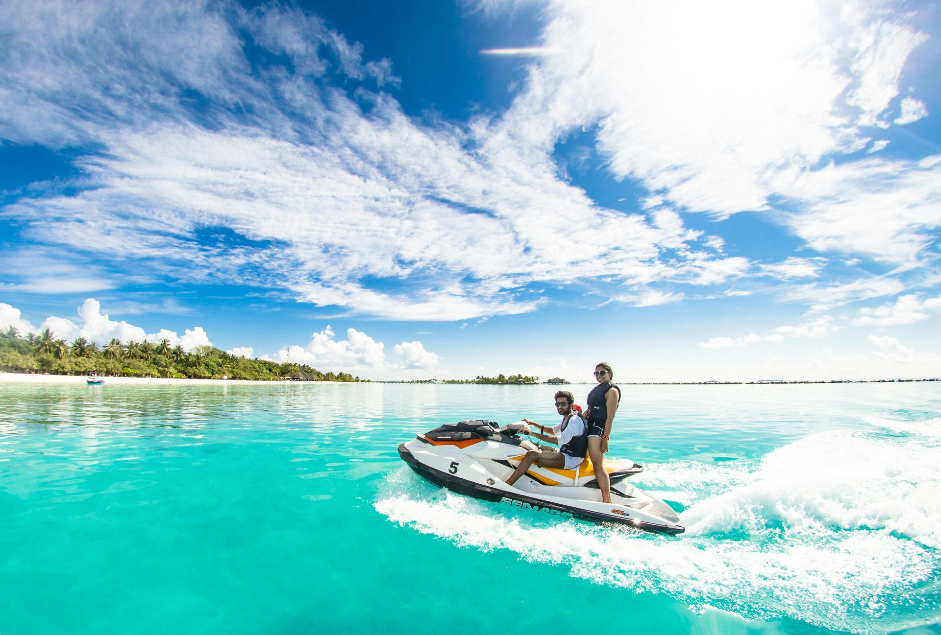 A couple is riding a jet ski in the ocean.