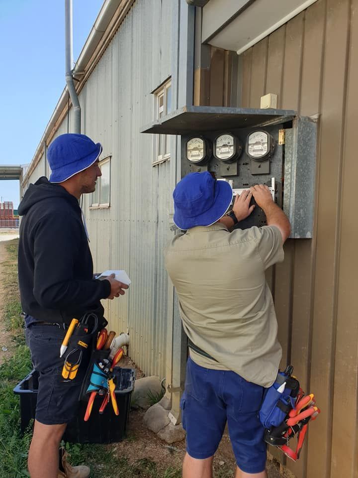 Two Men Are Working on An Electrical Box on The Side of A Building — Jason Jeffrey Electrical in South Tamworth, NSW