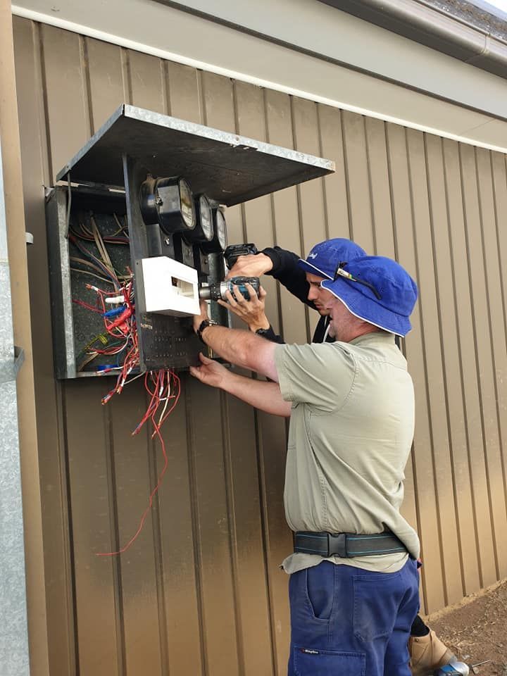 A Man Is Working on An Electrical Box on The Side of A Building — Jason Jeffrey Electrical in South Tamworth, NSW