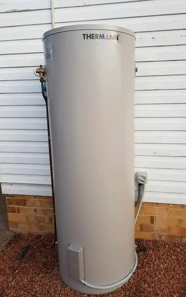 A Large Gray Water Heater Is Sitting in Front of A White House — Jason Jeffrey Electrical in South Tamworth, NSW