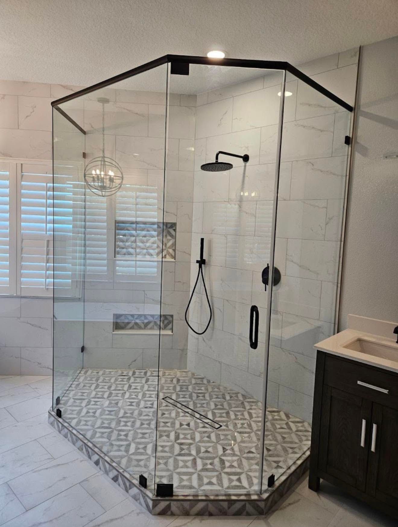 Glass corner shower with black trim and patterned tile floor in a modern bathroom