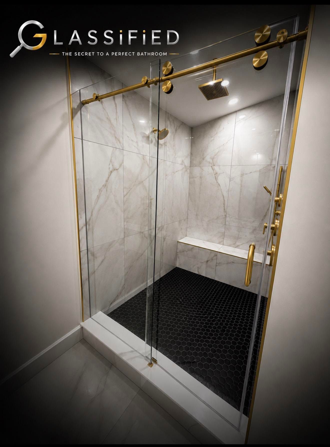Glass-enclosed shower with marble walls, black floor mat, and gold fixtures.