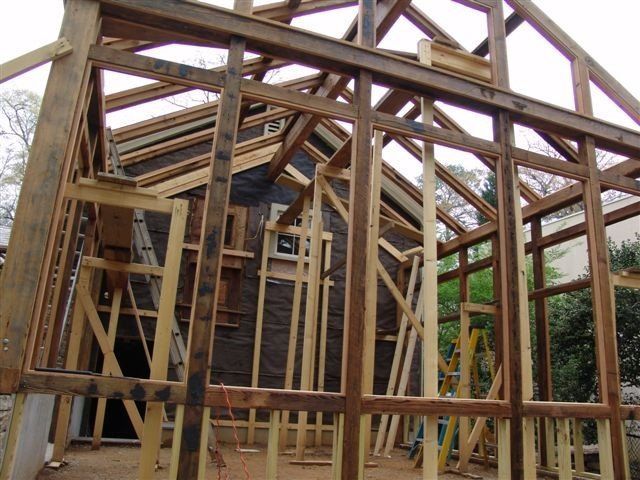 Wooden framing of a building under construction, with visible roof and window structures.