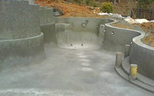 Empty concrete swimming pool under construction outdoors.
