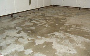 Wet concrete floor in a room with metal supports along the walls.