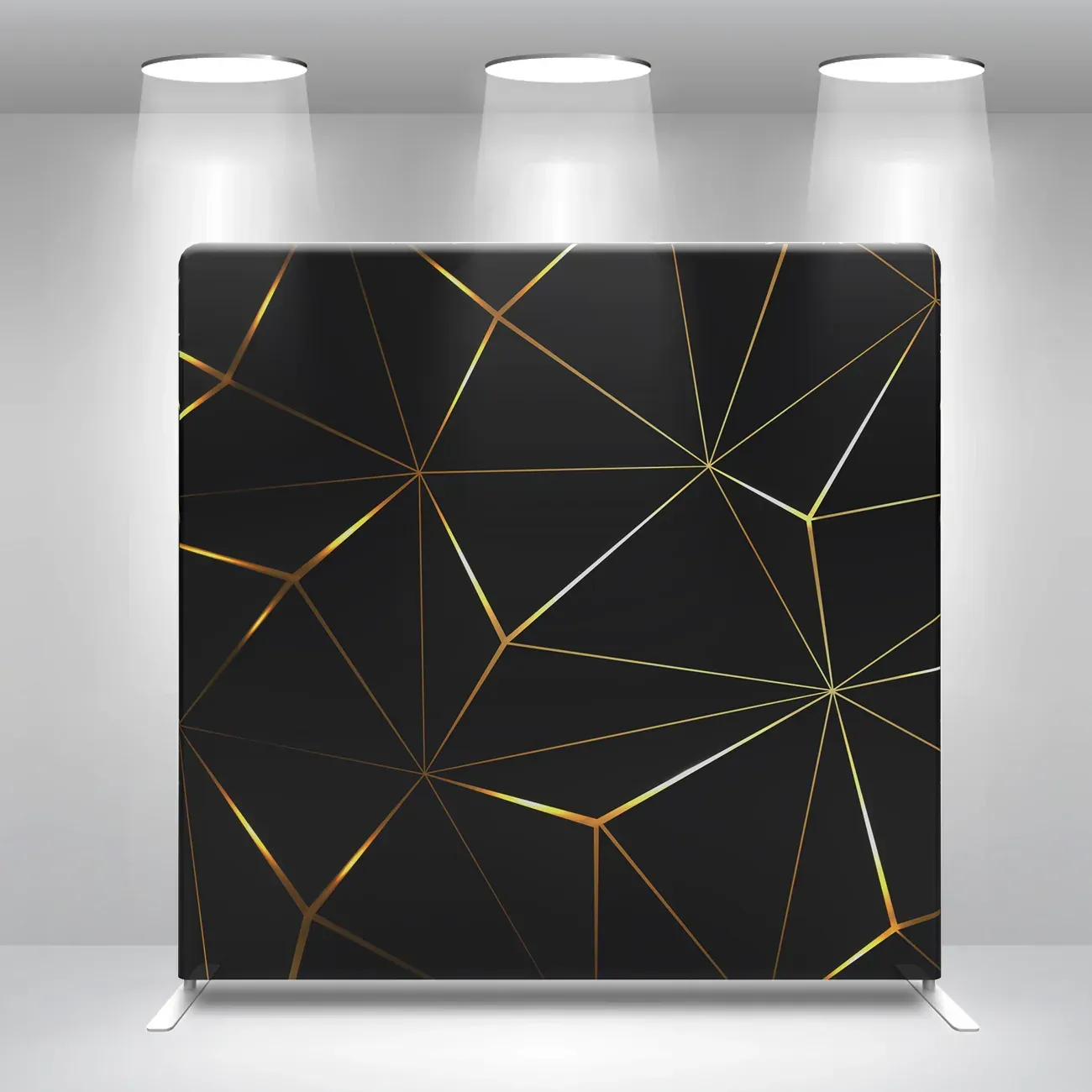 A black and gold backdrop with a geometric pattern is in a room with spotlights.