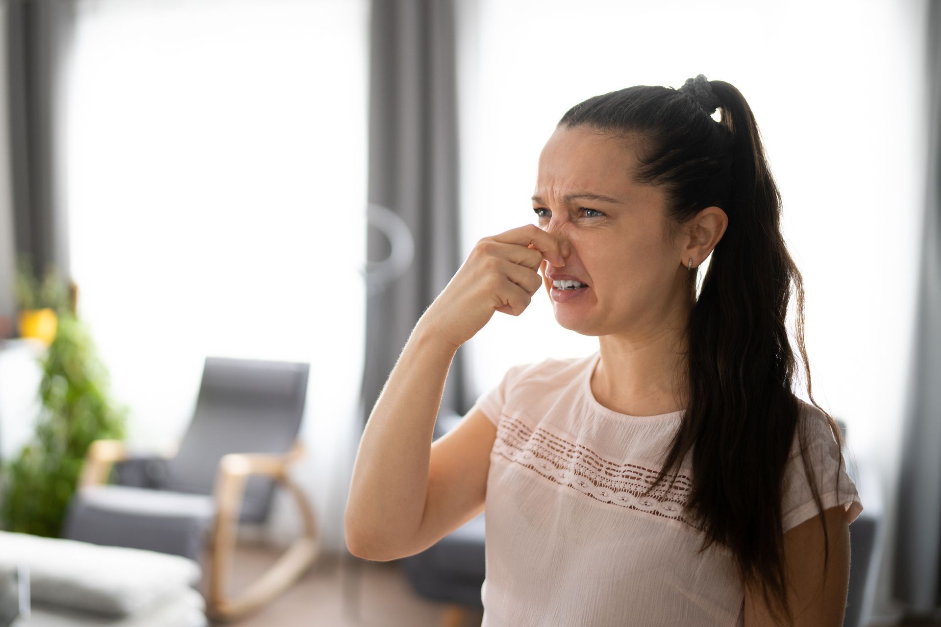 A woman is covering her nose with her hand in a living room.