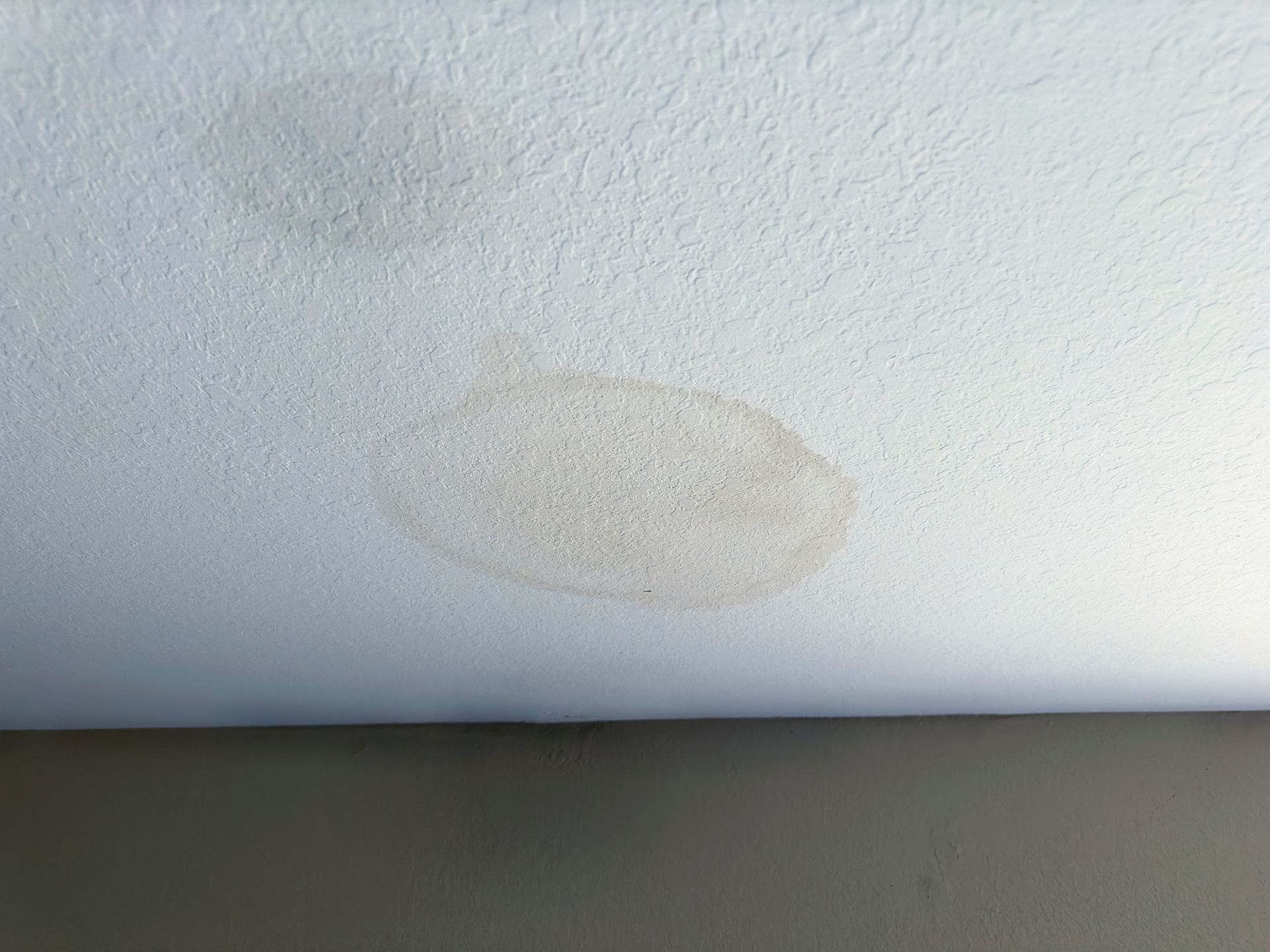 A close up of a white wall with a stain on it.