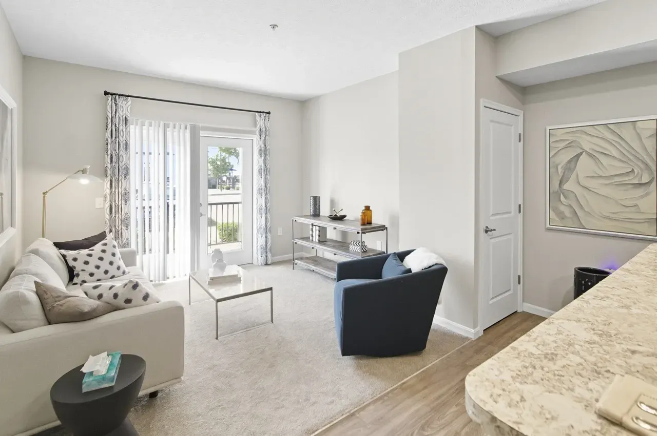 Living room with a white sofa, blue armchair, coffee table, and a balcony view.
