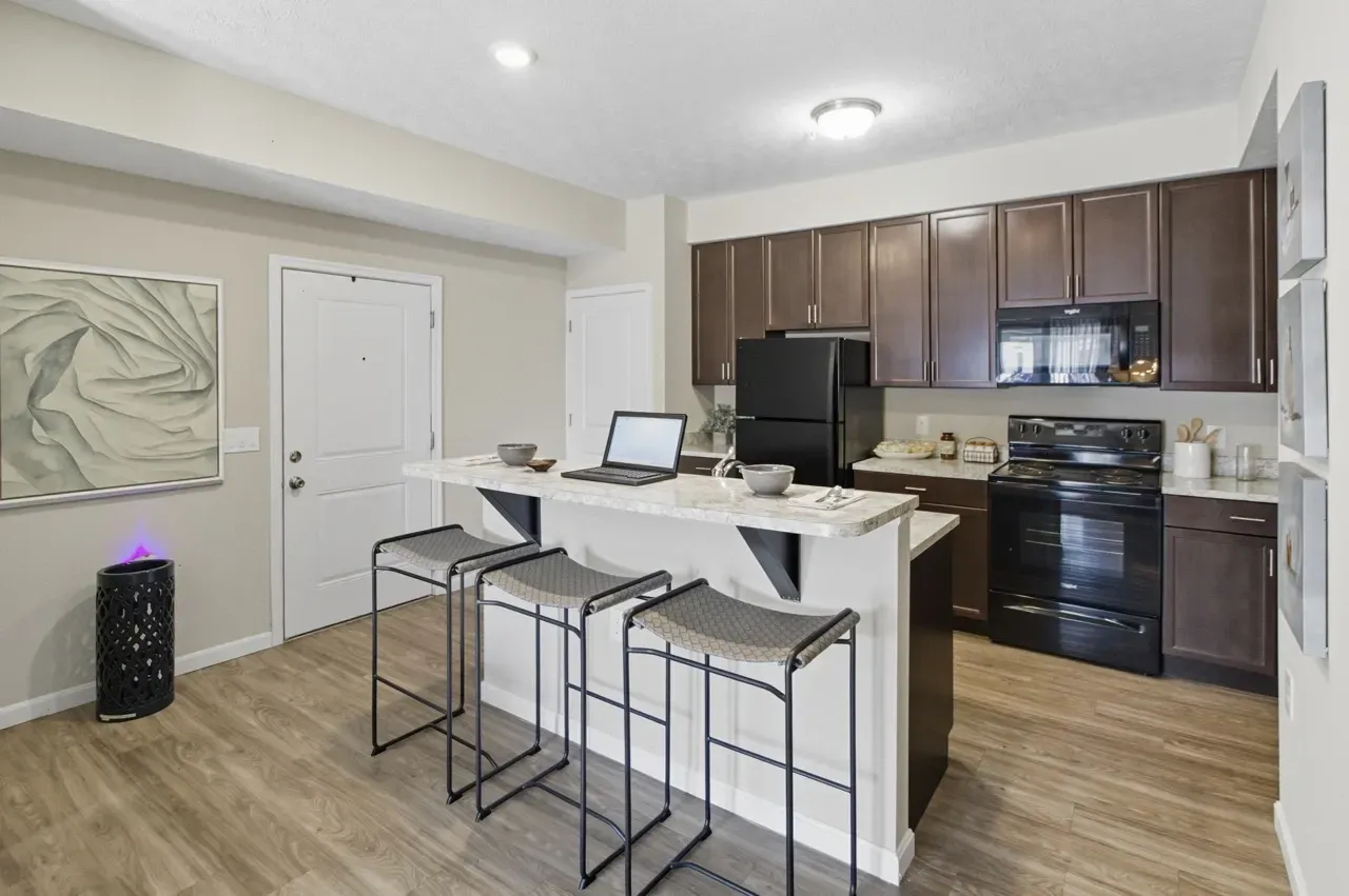 Modern kitchen with dark wood cabinets, a granite-topped island with bar stools, and stainless steel appliances.