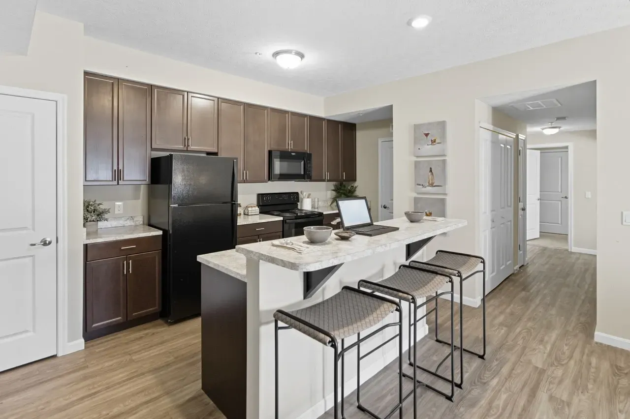 Modern kitchen with dark cabinets, black appliances, and a breakfast bar with stools.