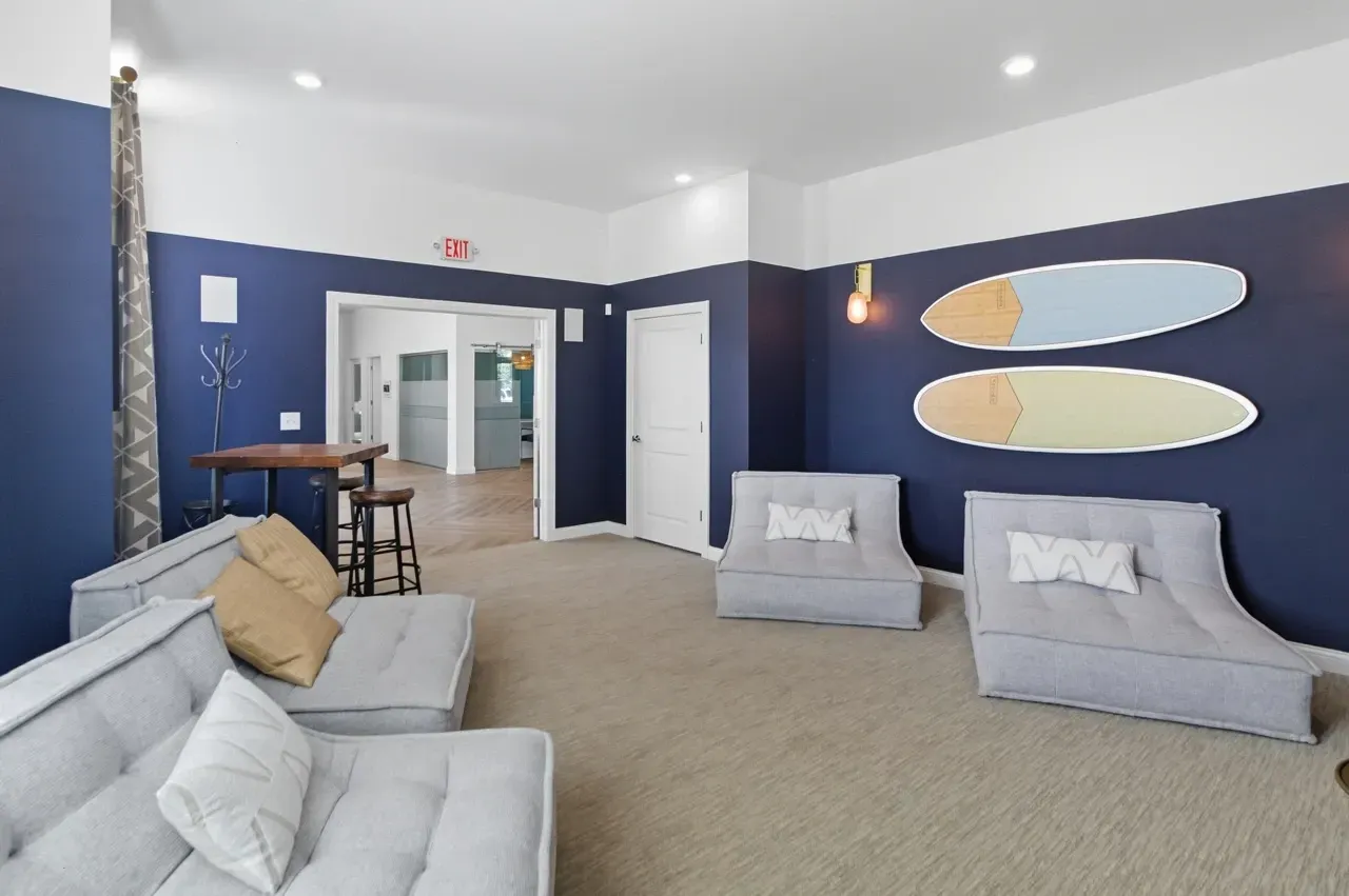 Lounge area with comfortable seating, a high-top table, and surfboards mounted on the wall.
