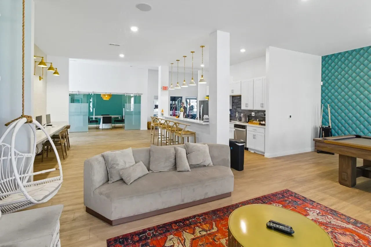 Modern lounge area with a pool table, comfortable seating, and a full kitchen.