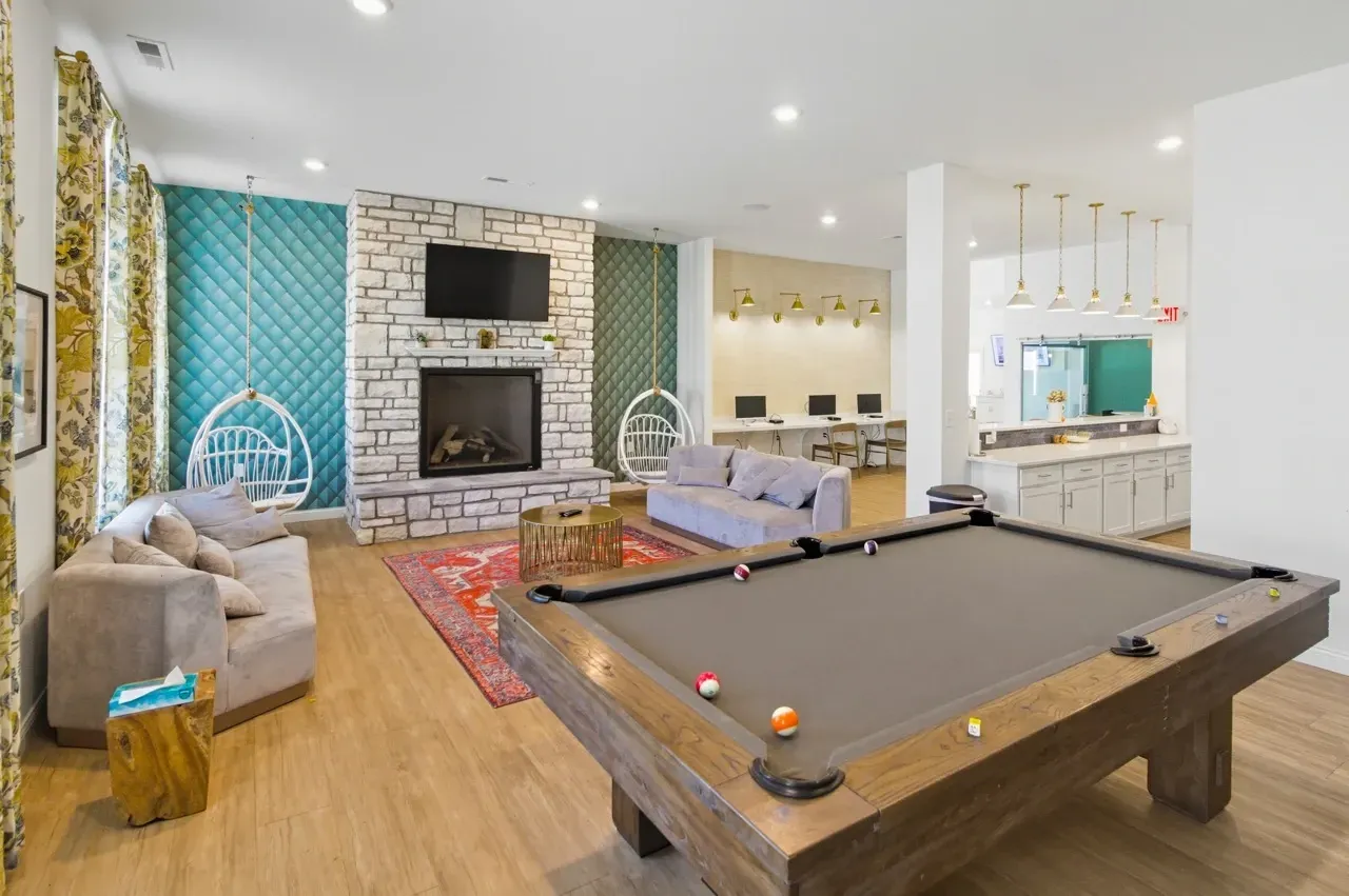 Community lounge area with a pool table, fireplace, seating, and a computer work station.