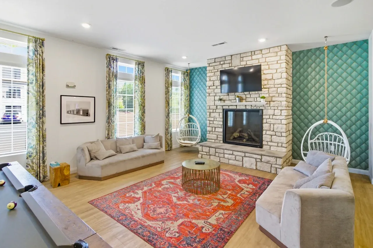 Lounge area with fireplace, pool table, sofas, and hanging chairs.