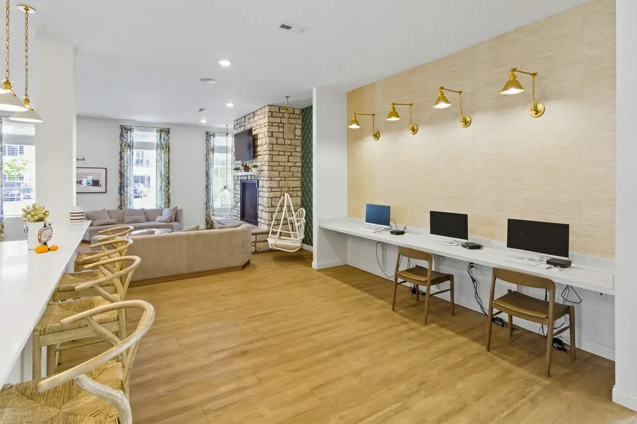 Community lounge area with a bar, fireplace, seating, and a computer workstation.