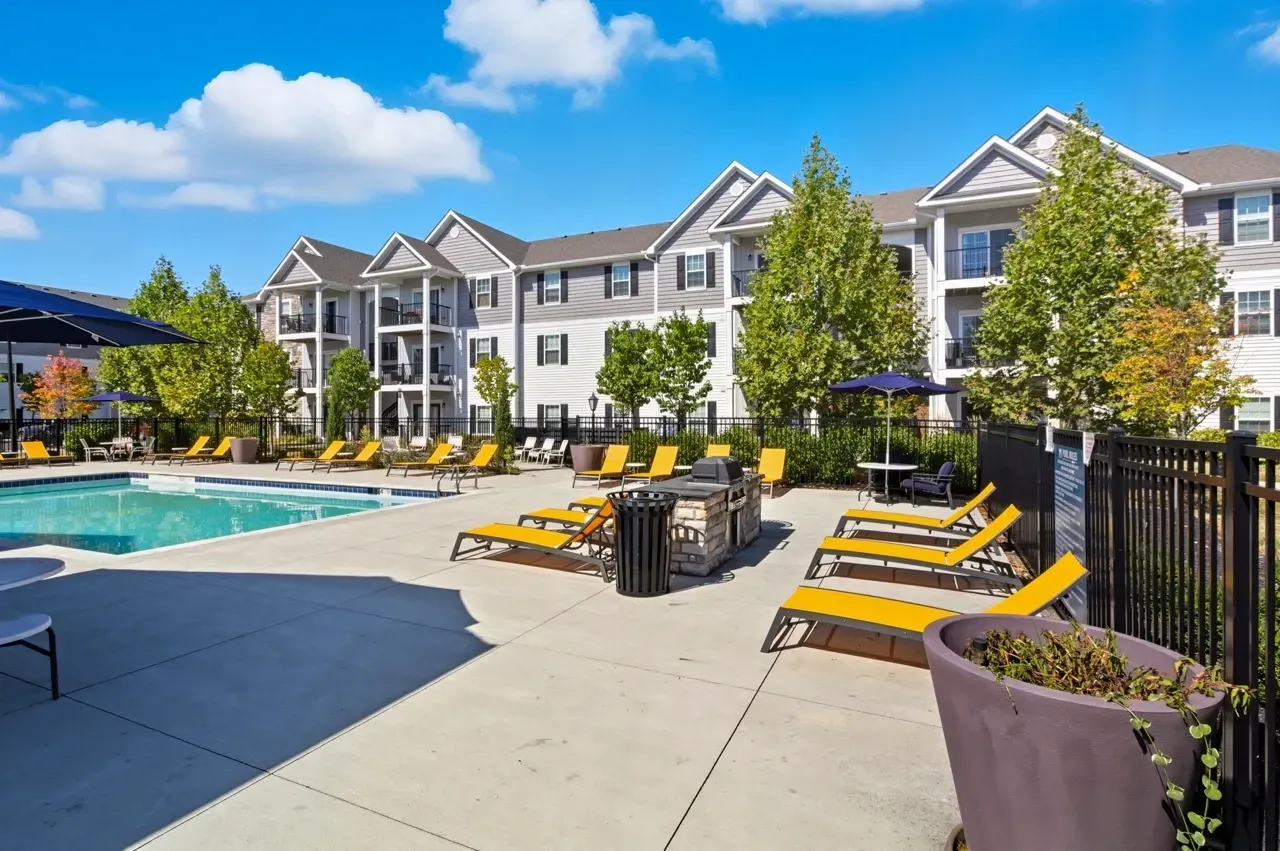 Apartment complex with outdoor swimming pool and lounge chairs.