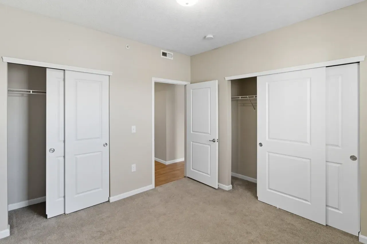 Closet doors in a bedroom. Two sliding doors on the right and left, and one hinged door in the center.