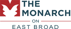 Logo for The Monarch on East Broad, featuring a red letter M shaped like a butterfly next to dark blue text.