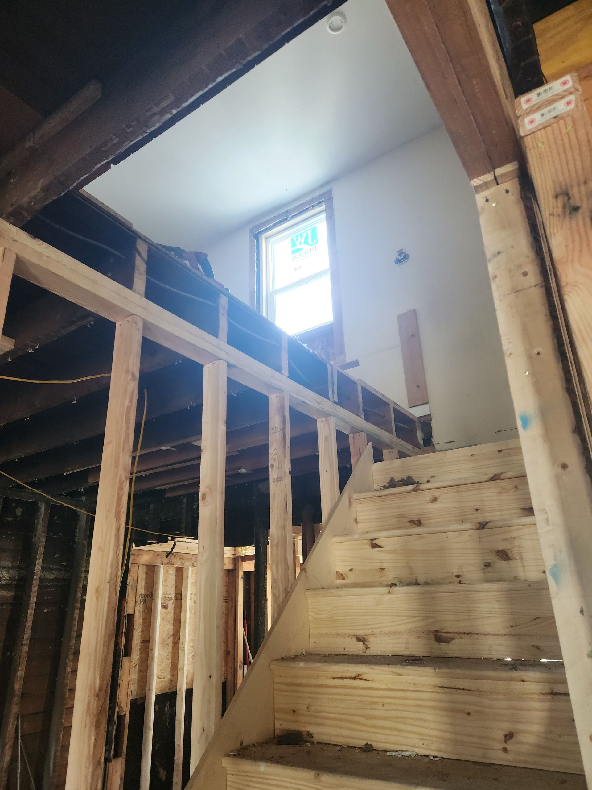 Staircase under construction with a window at the top. Wooden structure is visible, with beams and studs.