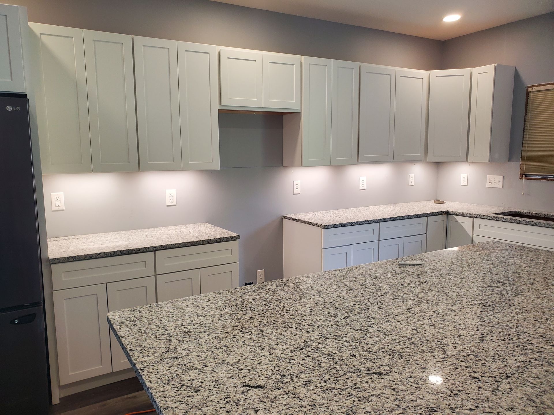 Gray kitchen with granite countertops and light-colored cabinets.