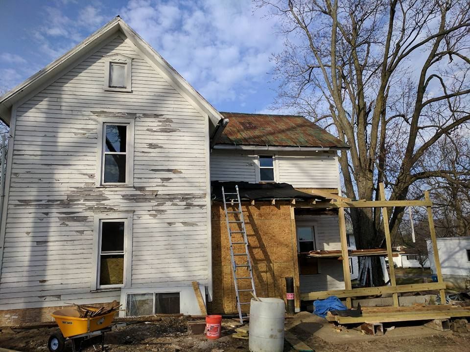 A two-story white house under construction. A ladder leans against the side of the house.