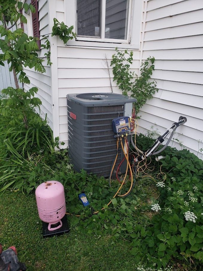 Air conditioning unit being serviced outside a white house, with pink refrigerant tank and equipment.