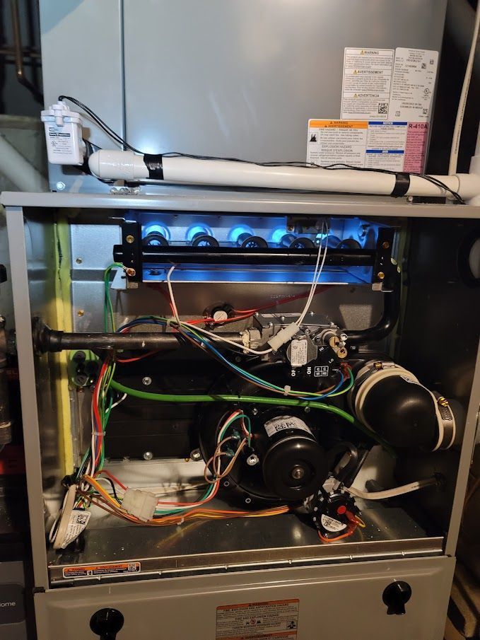 Gas furnace with blue flames, open, showing internal components and wiring.