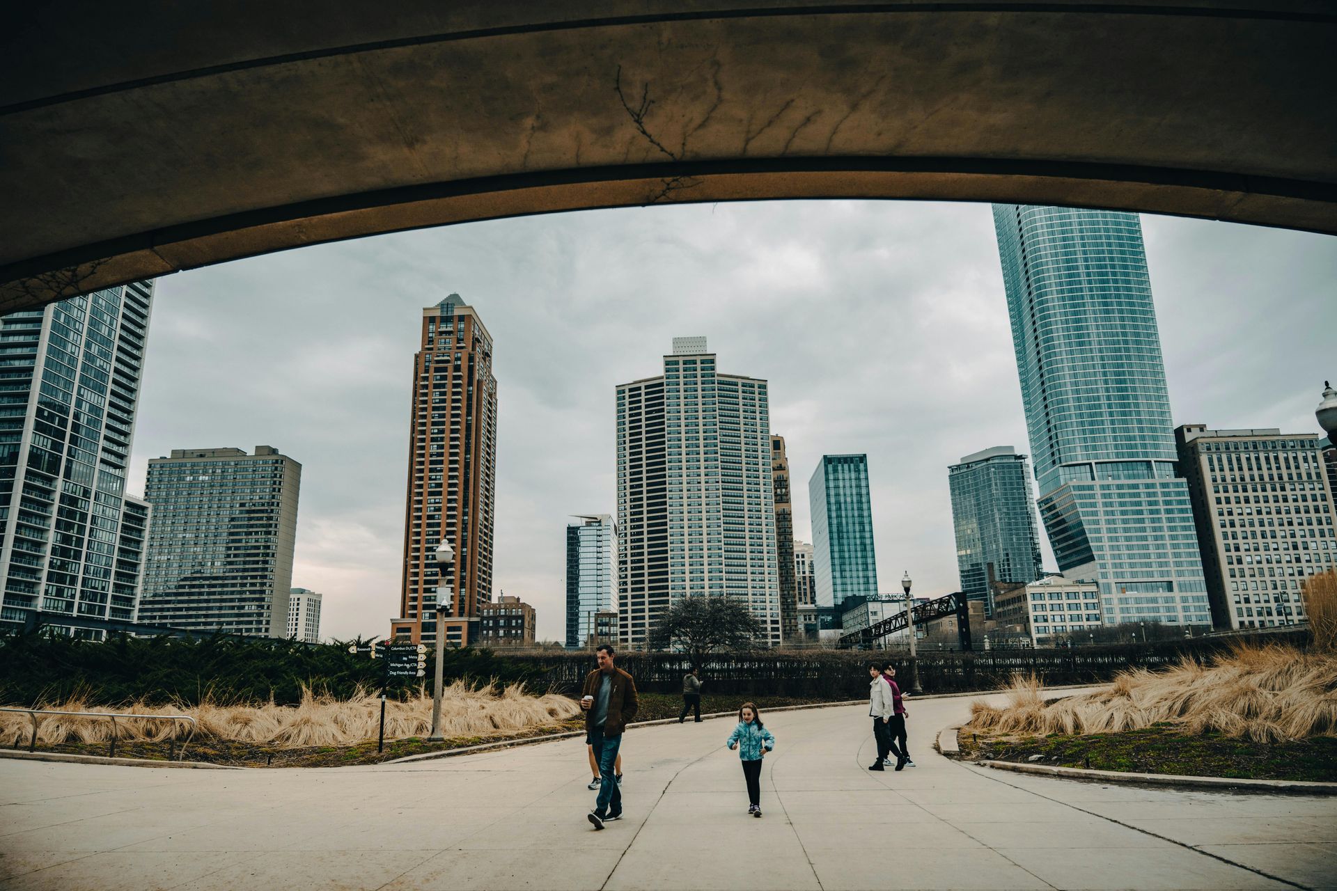 A group of people are walking down a path in front of a city skyline.