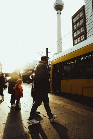 A person in a mustard shirt sits on a tiled floor with a child, both looking out a glass door toward a wooden deck.