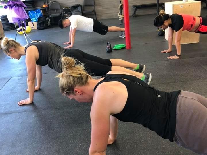 A group of people are doing push ups in a gym.
