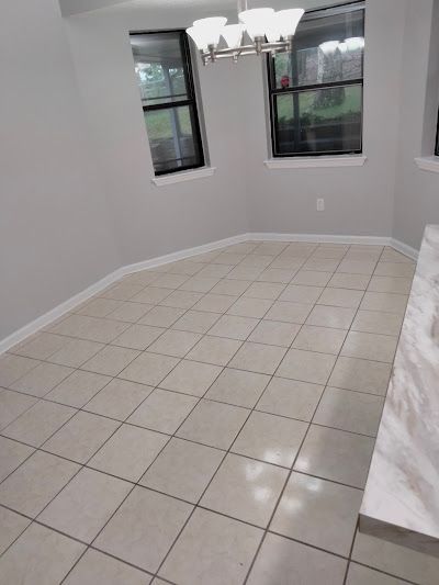 An empty dining room with tile floors and two windows.