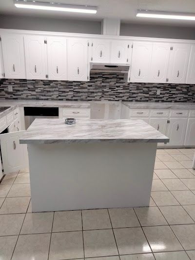 A kitchen with white cabinets and a large island in the middle.