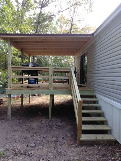 A mobile home with a wooden deck and stairs attached to it.