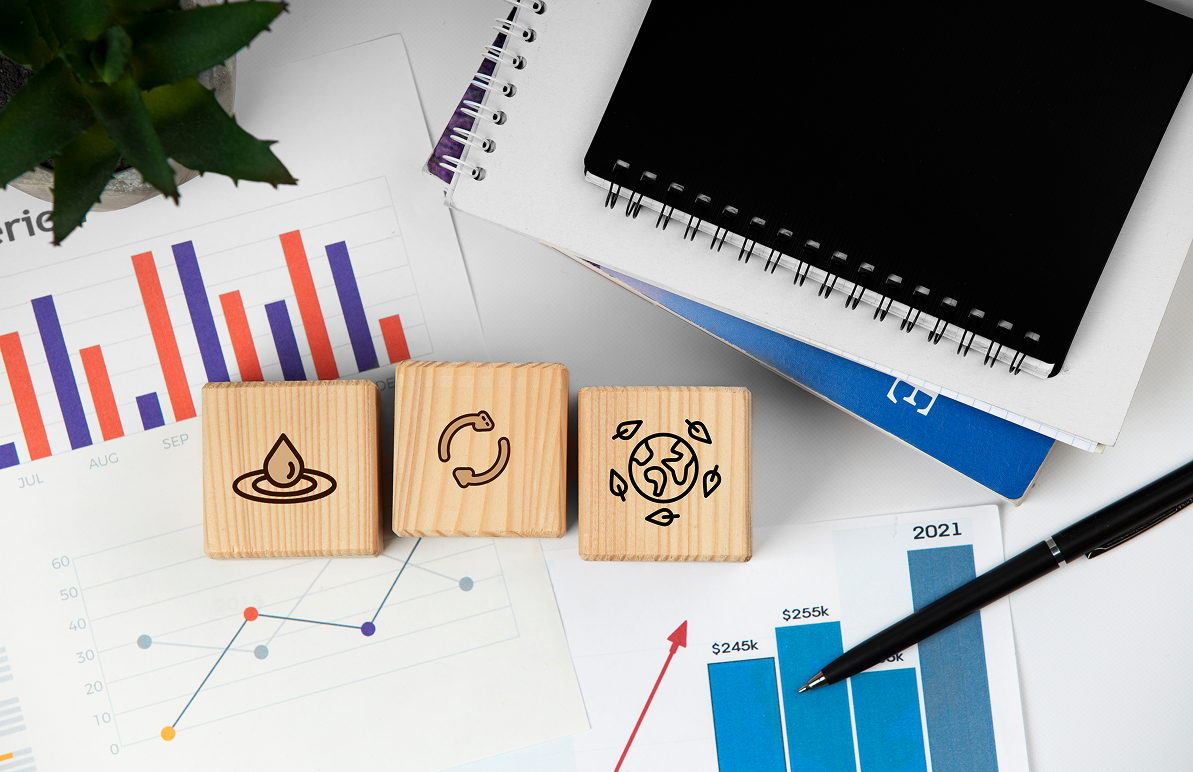 Man with beard in blue plaid shirt filming a video in a home studio. Camera and lamp in foreground.