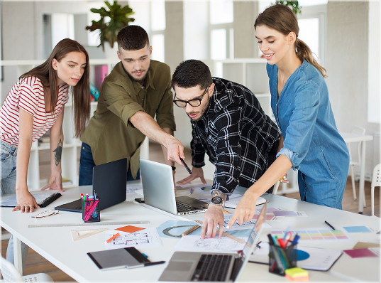 Man color-correcting video footage on dual monitors at a desk; he's in a dark room with a coffee cup.
