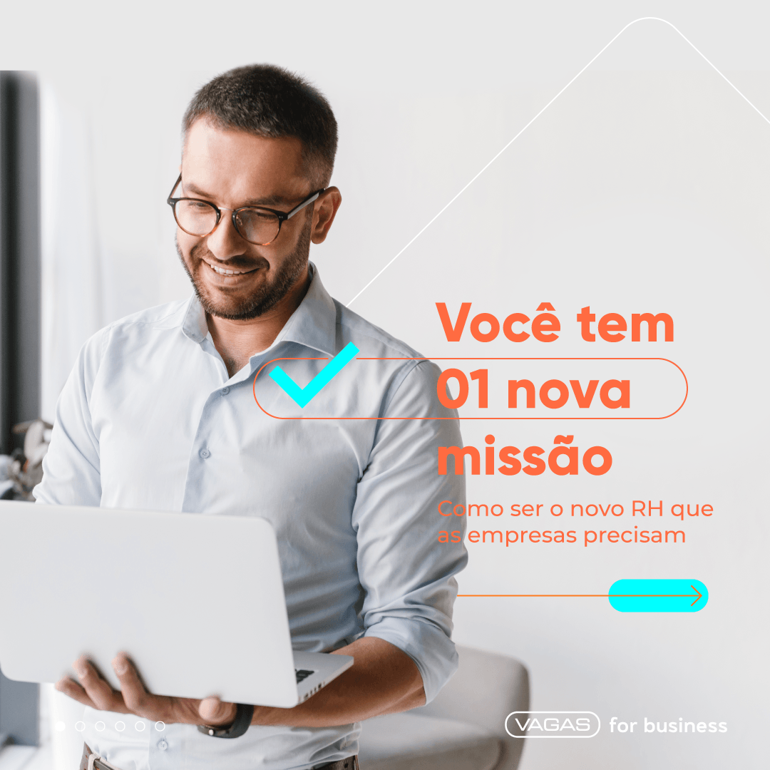 Um homem está segurando um laptop nas mãos e sorrindo.