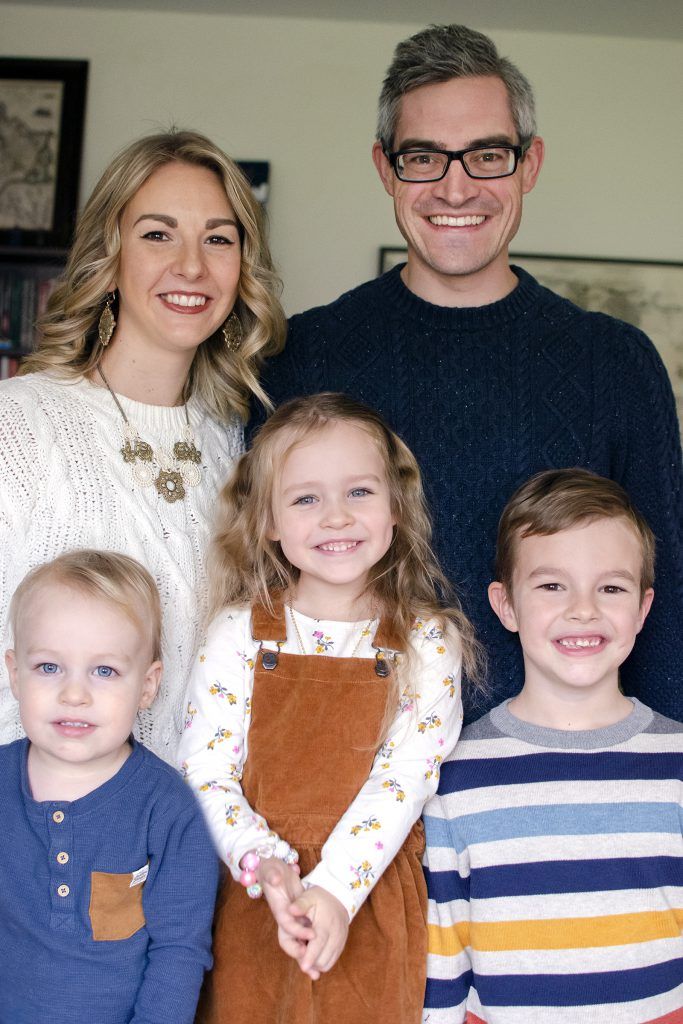 A family is posing for a picture together in a living room.