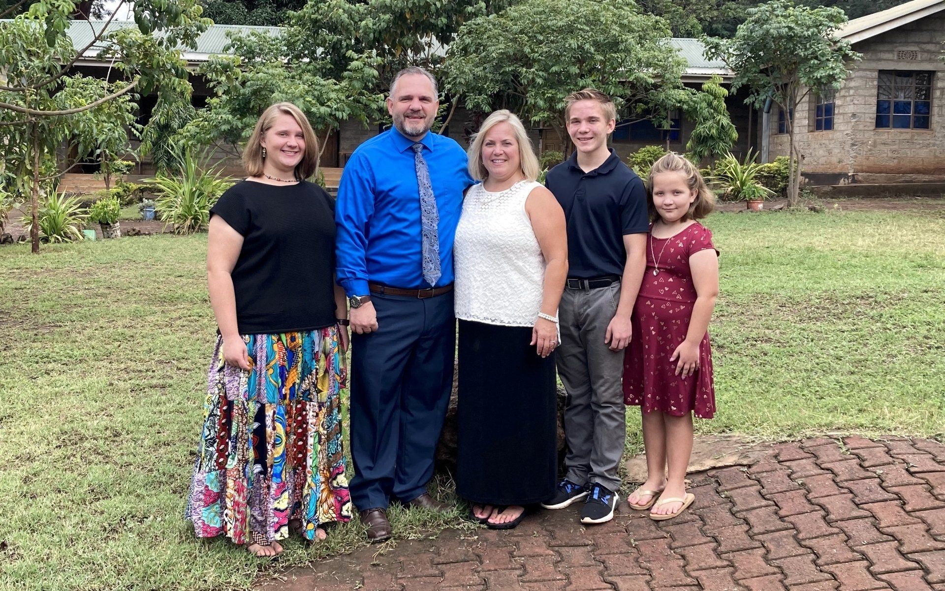 A family is posing for a picture in front of a house.